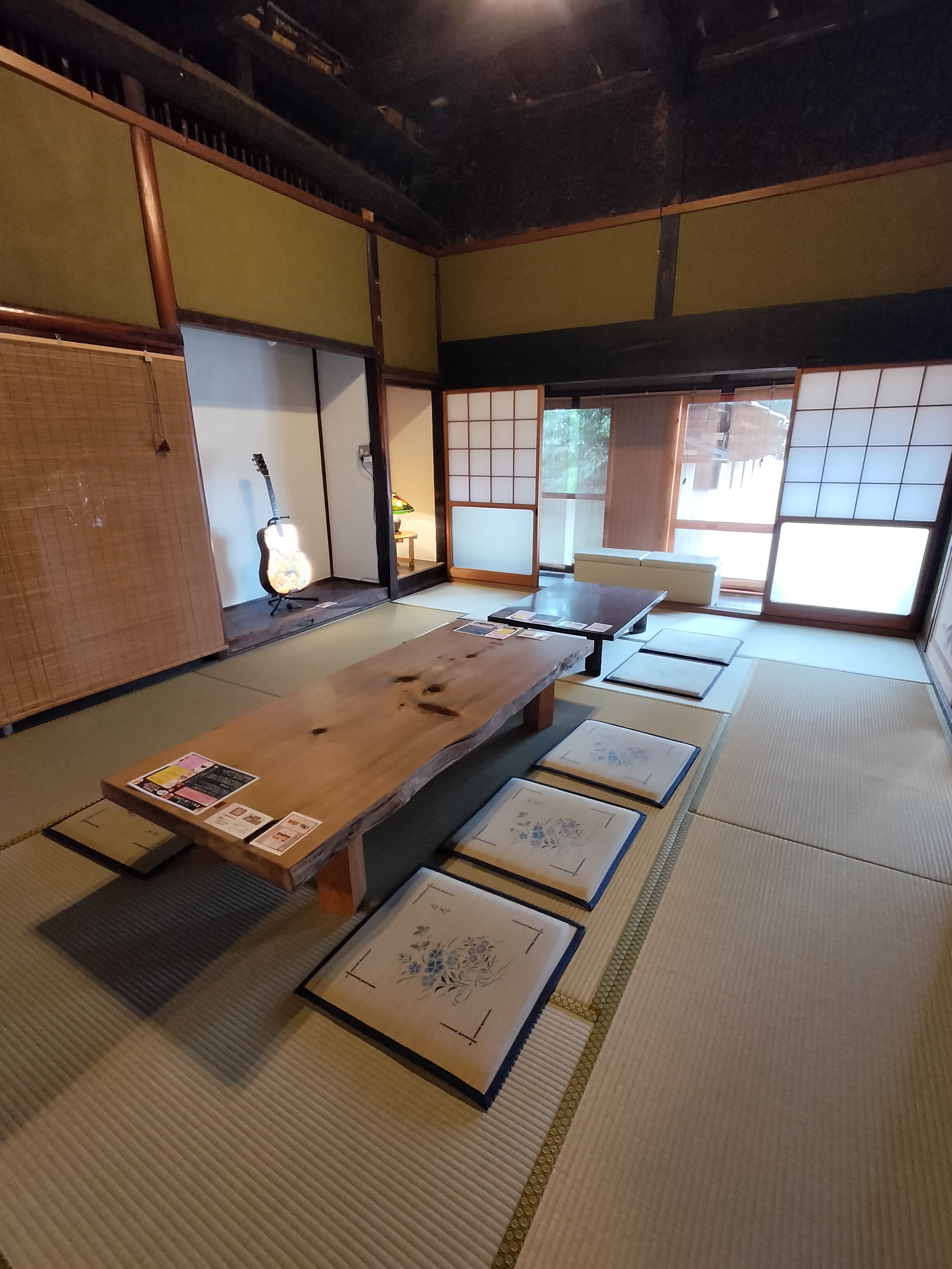 梁の見える和室に座卓と座布団が並ぶ古民家こだわりの室内