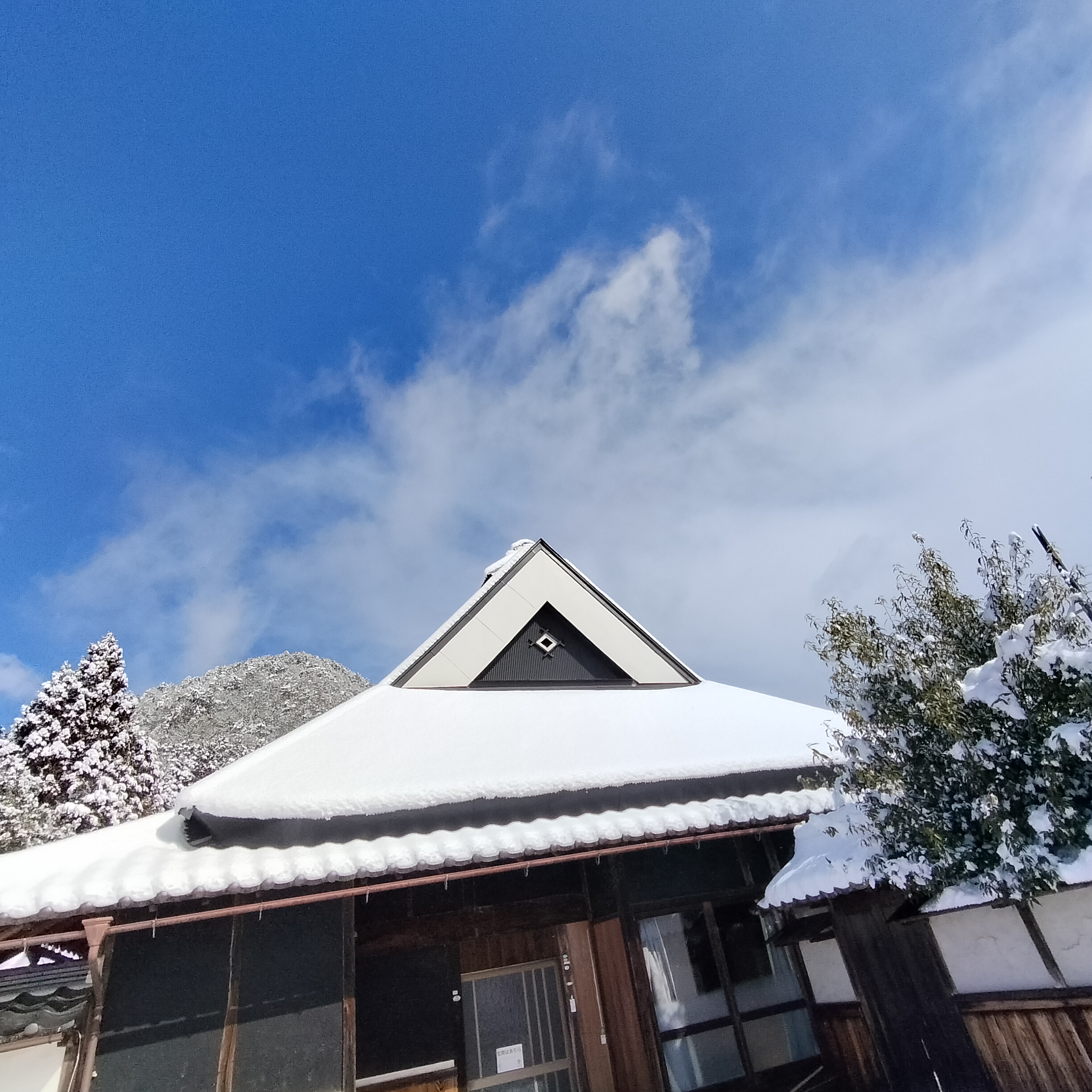 雪をかぶった古民家こだわりの屋根と丹波の山並み