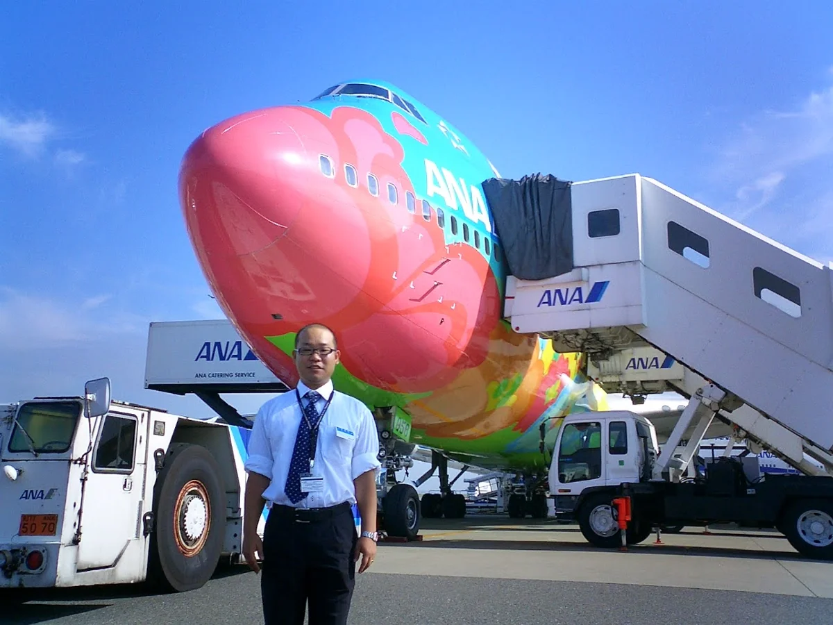 会社員時代、飛行機のそばに立つよっしー
