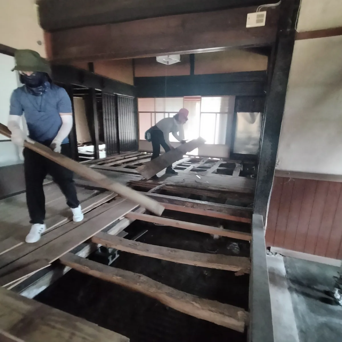 仲間と一緒に古民家の床を解体する作業風景